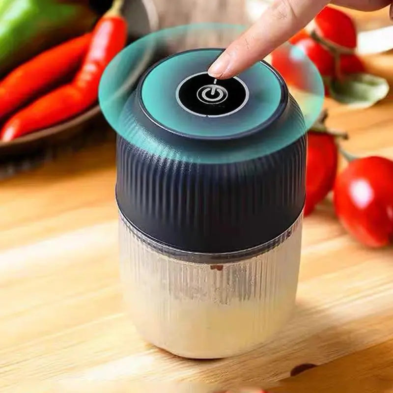 Navy electric mini food chopper with lid pressed by hand; clear cup with mixture
