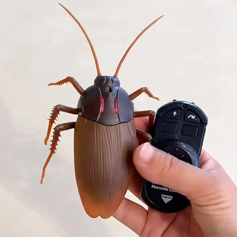 Remote control cockroach toy with brown body and dark head, held with a black controller