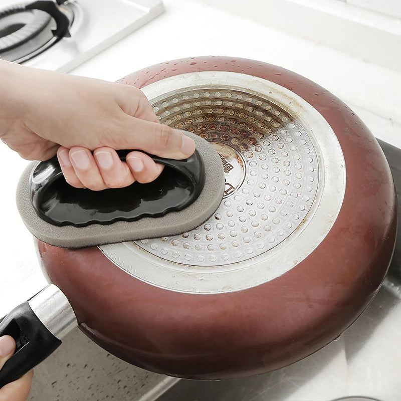 Rust eraser sponge brush scrubbing a stainless pan with built-up residue